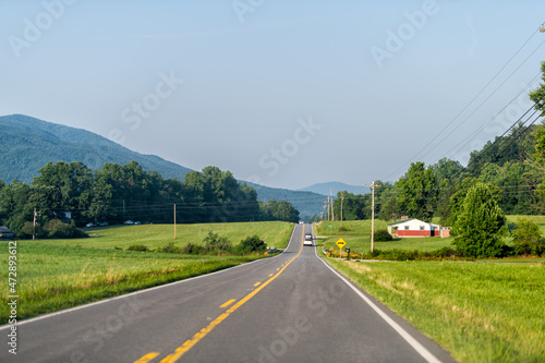 North Carolina highway road with blue sky near Blue Ridge Mountains parkway with countryside rural country scenery in Marion, McDowell County on US-221 and green farm fields, houses in summer photo