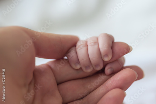 mom's hand holds the handle of a newborn baby