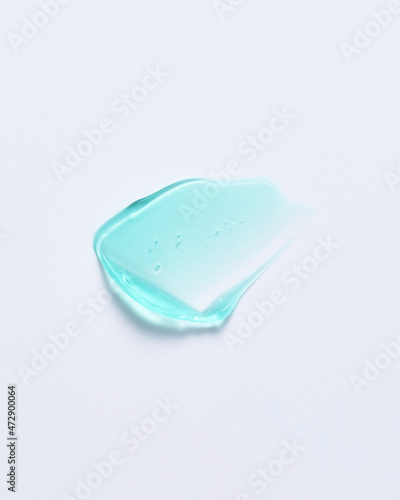 Drop of  green gel cosmetics product smudged with spatula on white backdrop