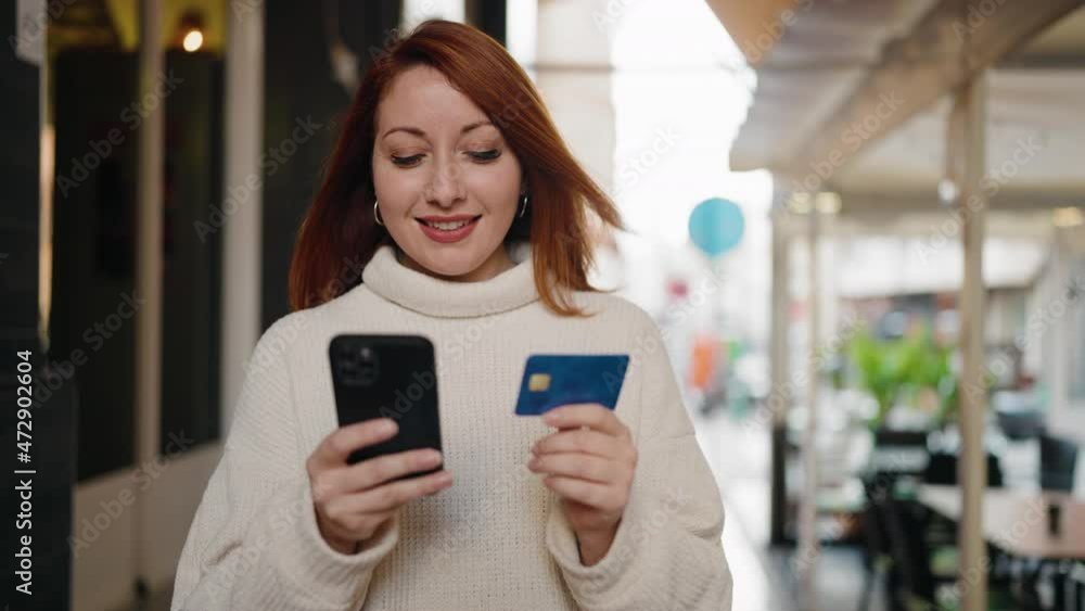 Young redhead woman using smartphone and credit card at street Young redhead woman using smartphone and credit card at street