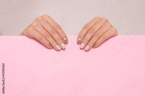 Beautiful female hands with beige manicure nails on pink background