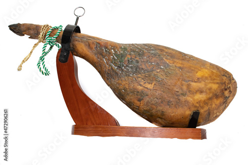 A leg of a Spanish Serrano ham, with a green and white twine, in a ham holder, isolated on white background. Laid on a white pillow, in concept like an angelic meal. photo