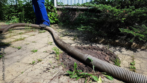 the worker opened the sewer hatch and inserted a hose for cleaning the septic tank. maintenance of communications in a private house. dirty work