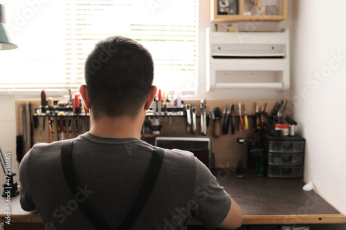 instrument repairman seen from behind working at his workbench