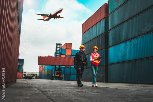 Industrial worker works with co-worker at overseas shipping container port . Logistics supply chain management and international goods export concept . photo