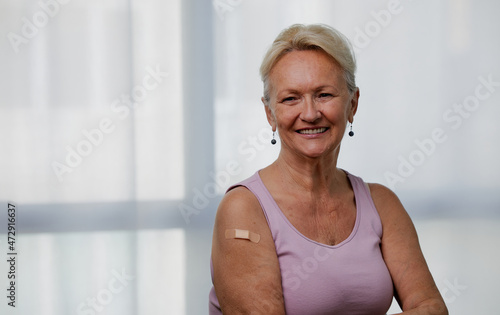 Fototapete Senior woman wearing face mask showing vaccinated arm with adhesive bandage plaster
