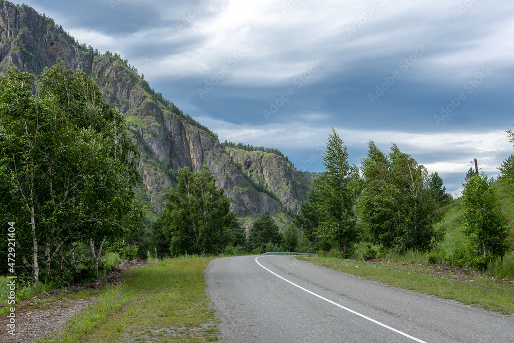 Fototapeta premium asphalt road between mountain peaks. warm summer day