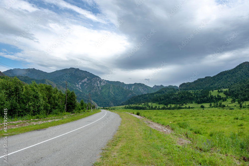asphalt road between mountain peaks. warm summer day