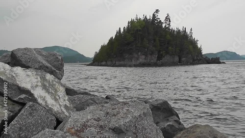 Video of an island in the Bic park on a foggy day, with rocks in the foreground and the river churning