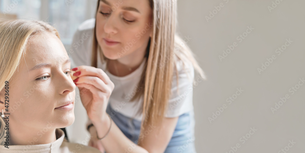 blond young woman model sitting in a beauty studio. make-up artist applying CC cream on her face. skin correction. make up in salon.copy space blond young woman model sitting in a beauty studio. make-up artist applying CC cream on her face. skin correction. make up in salon.copy space