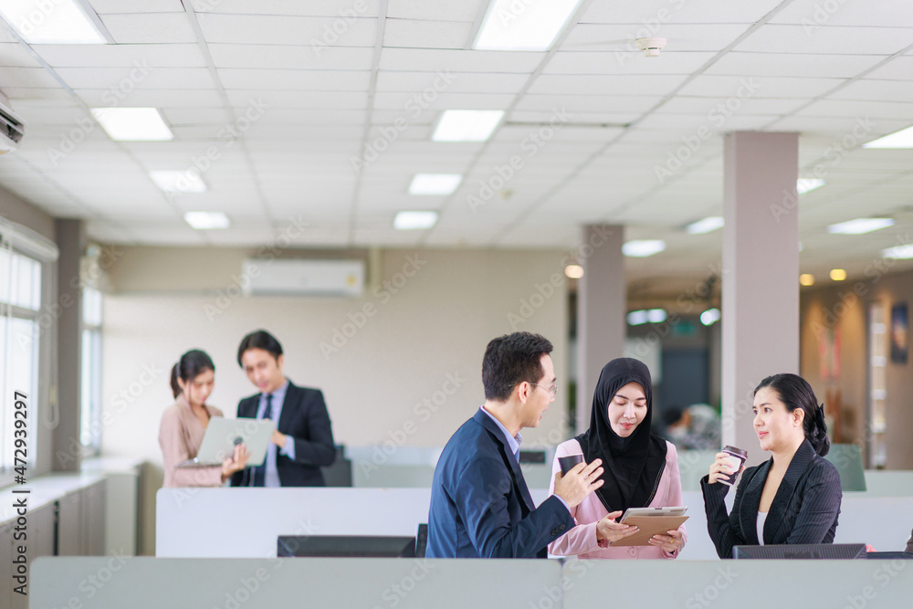Asian officer talking with their coworker in the office while having a coffee break. Asian officer talking with their coworker in the office while having a coffee break.