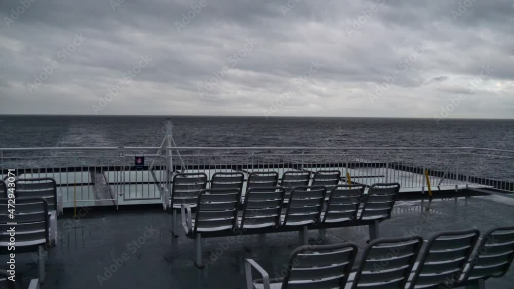 Rear view of ferry vessel cruising on Inside Passage on the coast of British Columbia, Canada in the Pacific Ocean on cloudy day in autumn season with empty seats and railing. Rear view of ferry vessel cruising on Inside Passage on the coast of British Columbia, Canada in the Pacific Ocean on cloudy day in autumn season with empty seats and railing.