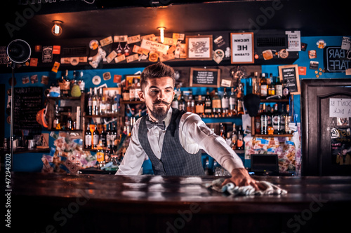 Experienced barman demonstrates the process of making a cocktail while standing near the bar counter in nightclub