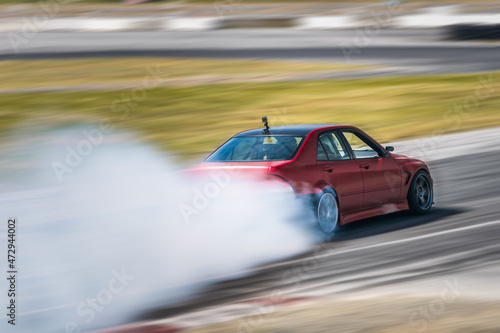 Red Drift Car / Race car drifting around corner very fast with lots of smoke from burning tires on speedway / racetrack / drift track. Lexus is300 v8. JDM car.