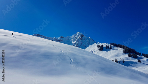 Ski mountaineer hiking up a summit in the Austrian Alps on a beautiful winter day. Walsertal, Vorarlberg, Austria.