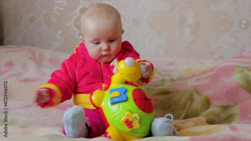 baby with a musical toy is playing,baby playing with a turtle toy on the bed baby with a musical toy is playing,baby playing with a turtle toy on the bed