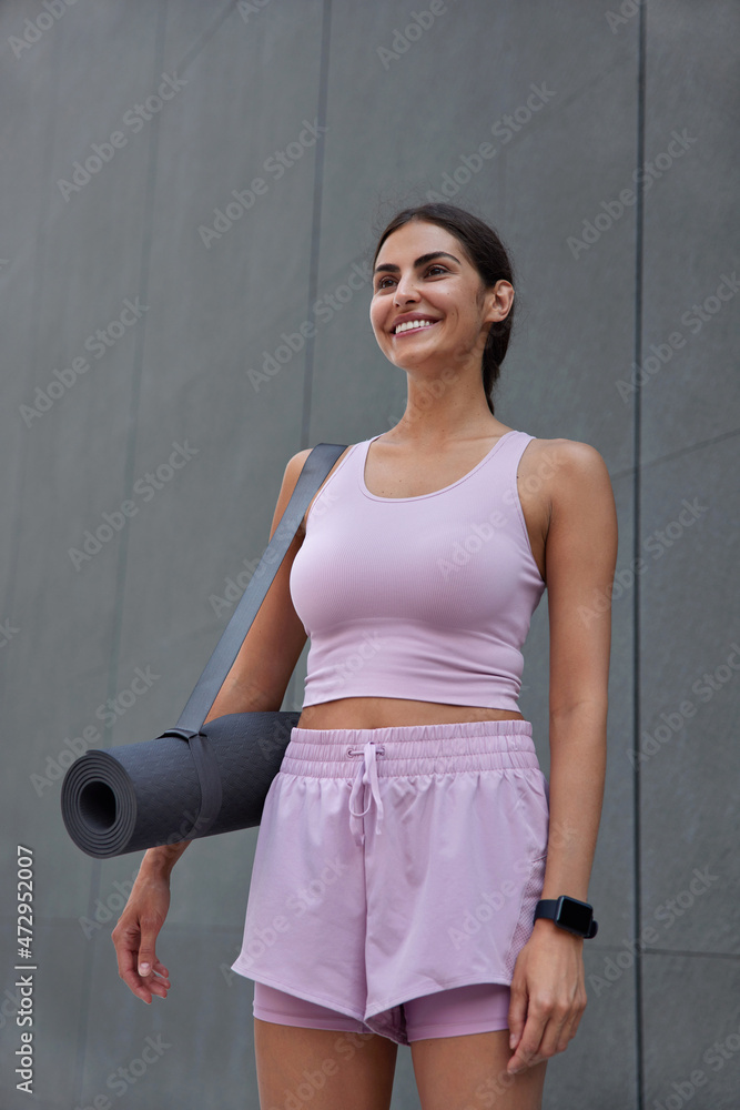 custom made wallpaper toronto digitalVertical shot of motivated happy woman has fit body carries rolled karemat dressed in top shorts poses against grey wall has glad smile on face after cardio training. Yoga instructor ready for session