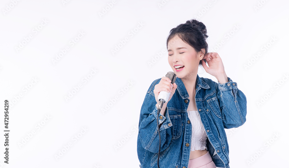 Cheerful young woman holding microphone in own hands enjoyment sing song while standing over isolated white background. Lifestyle hobby entertainment concept. Cheerful young woman holding microphone in own hands enjoyment sing song while standing over isolated white background. Lifestyle hobby entertainment concept.