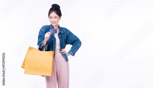 Payment finance electronic concept. Excited cheerful smile shopper young woman wear jacket jeans holding shopping bags paper showing credit card mockup while standing over isolated white background.