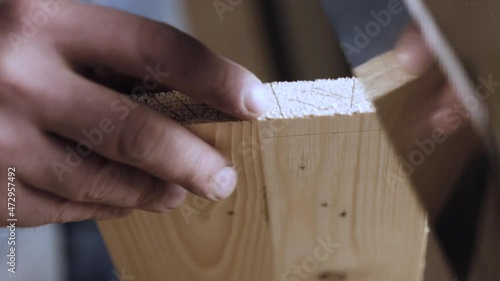 close up. carpenter cuts out a dovetail on a wood board with a hand saw. master makes a spike on a wooden board for a reliable connection of parts
