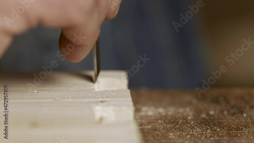 a carpenter cuts out a dovetail on a pine board with a chisel. dovetail joinery is done with a hand tool. woodworker makes an antique spike to connect parts