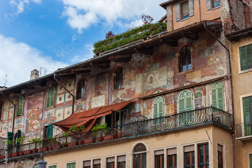 Colored facades of old buildings with balconies decorated with plants in the old part of Verona. Traditional Italian buildings