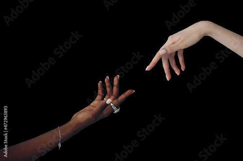 World Humanitarian Day. Caucasian white and African American black hand reaching out to each other on black background. photo