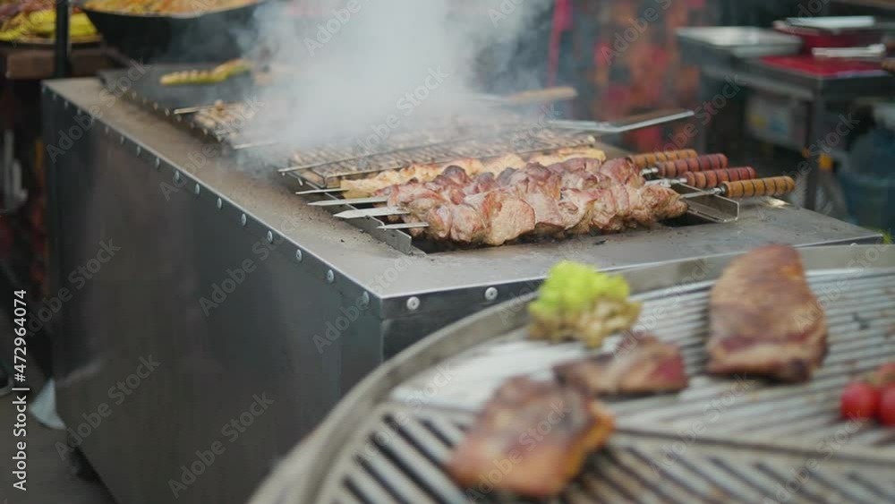 Meat on skewers and mushrooms are fried on the grill. Spinning barbecue for outdoor kitchen. Shish kebab and mushrooms are cooked on the grill Meat on skewers and mushrooms are fried on the grill. Spinning barbecue for outdoor kitchen. Shish kebab and mushrooms are cooked on the grill
