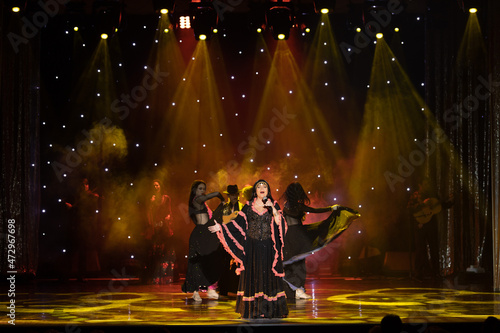 A team of musicians, singers and dancers in gypsy costumes singing and dancing on stage photo