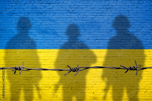 Flag of Ukraine painted on a brick wall with soldiers shadows. Relationship between Ukraine and Russia photo