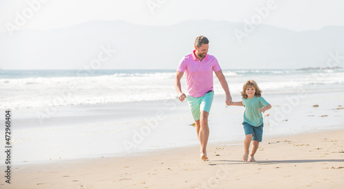 family of cheerful daddy man and child boy running on beach  activity