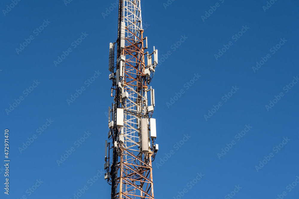 Cellphone tower with multiple antennas against a blue sky Cellphone tower with multiple antennas against a blue sky