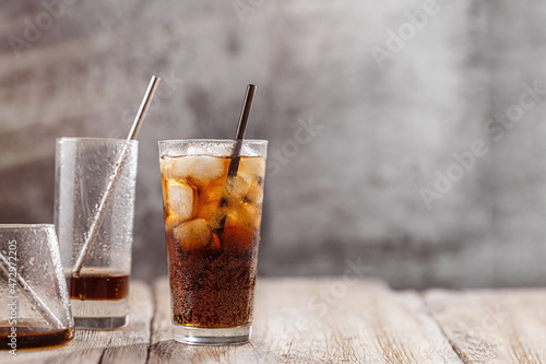 Cola with Ice Cubes Glasses. Glass of cola with ice cubes on wood table, soft drink. Copy Space.