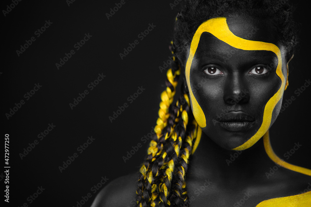 Yellow and black body paint. Woman with face art. Young girl with colorful bodypaint. An amazing afro american model with makeup. - obrazy, fototapety, plakaty 