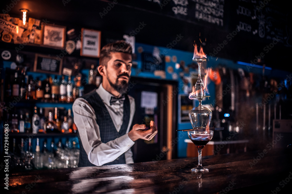 Charming barman demonstrates the process of making a cocktail behind bar