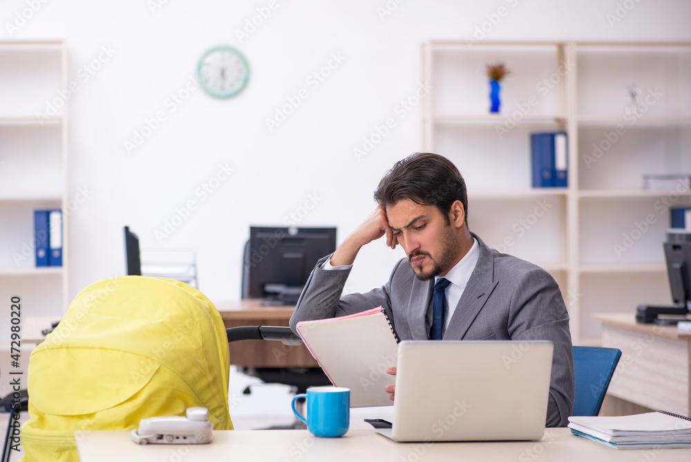 Young male employee looking after new born at workplace Young male employee looking after new born at workplace