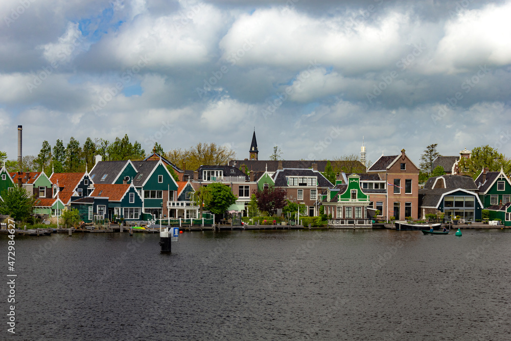 Beautiful small houses by the water with windmills in Zaanse Schans, Netherlands