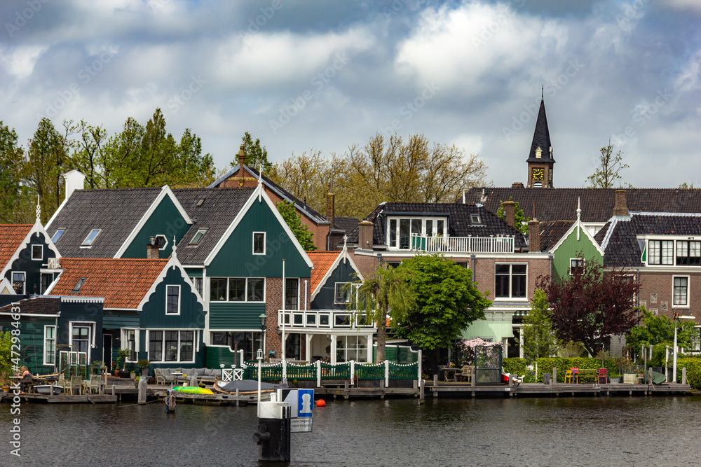 Beautiful small houses by the water with windmills in Zaanse Schans, Netherlands Beautiful small houses by the water with windmills in Zaanse Schans, Netherlands