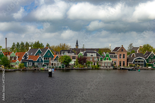 Beautiful small houses by the water with windmills in Zaanse Schans, Netherlands © Erol