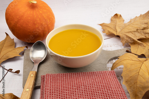 soupe au potiron avec feuilles d'automne et cuillère sur fond blanc photo