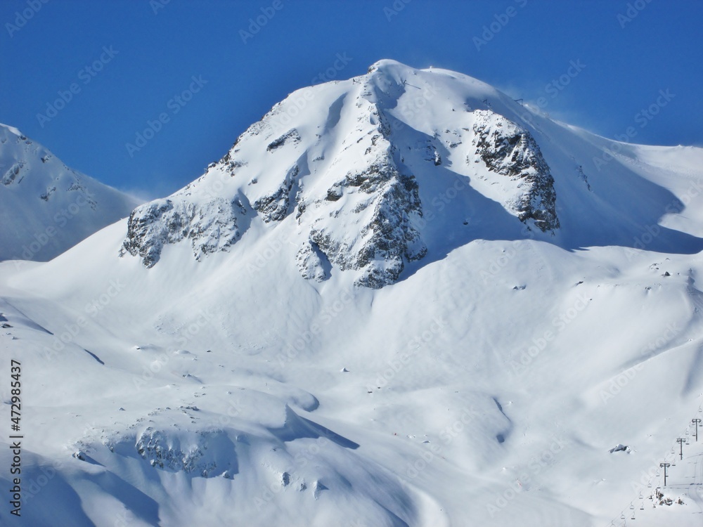 Beautiful view of snowcapped peaks and a chairlift. Mountains in winter time. Skiing area in the French Alps. Sunny day in ski resort. Les Sybelles. Holiday destination. Ski business. 