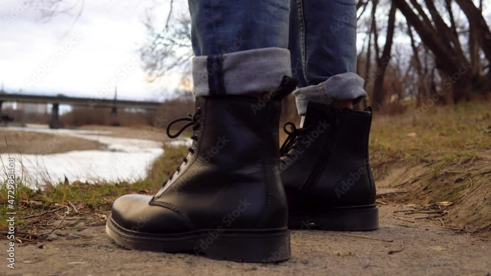 man in black leather boots on the background of the river man in black leather boots on the background of the river