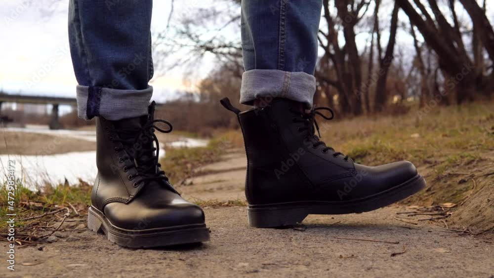 man in black leather boots on the background of the river man in black leather boots on the background of the river