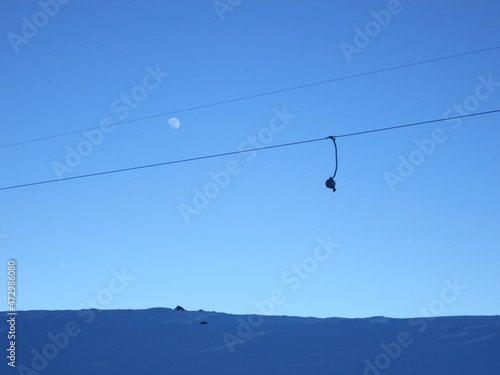 Moon in the evening time. Drag lift against the blue sky. High mountains. Nice evenign view.