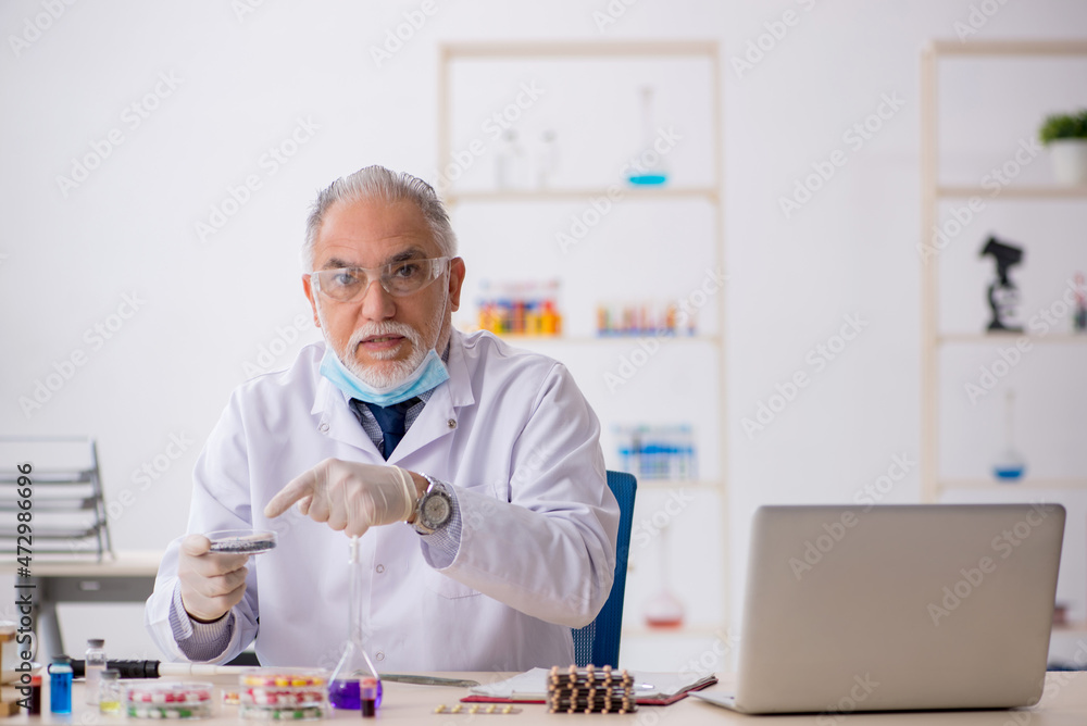 Old male chemist in drug synthesis concept Old male chemist in drug synthesis concept