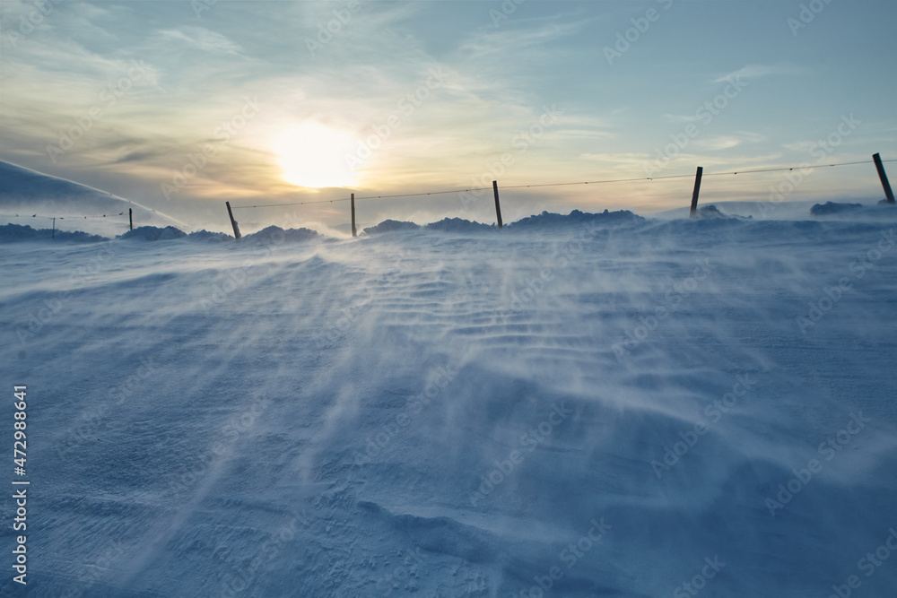 Winter snowy mountains with blizzard with limiters pillars in sunset. Winter background for design Winter snowy mountains with blizzard with limiters pillars in sunset. Winter background for design