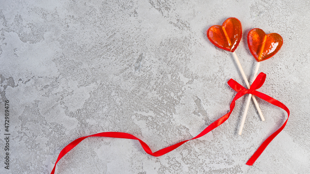 Two heart-shaped lollipops tied with a red ribbon