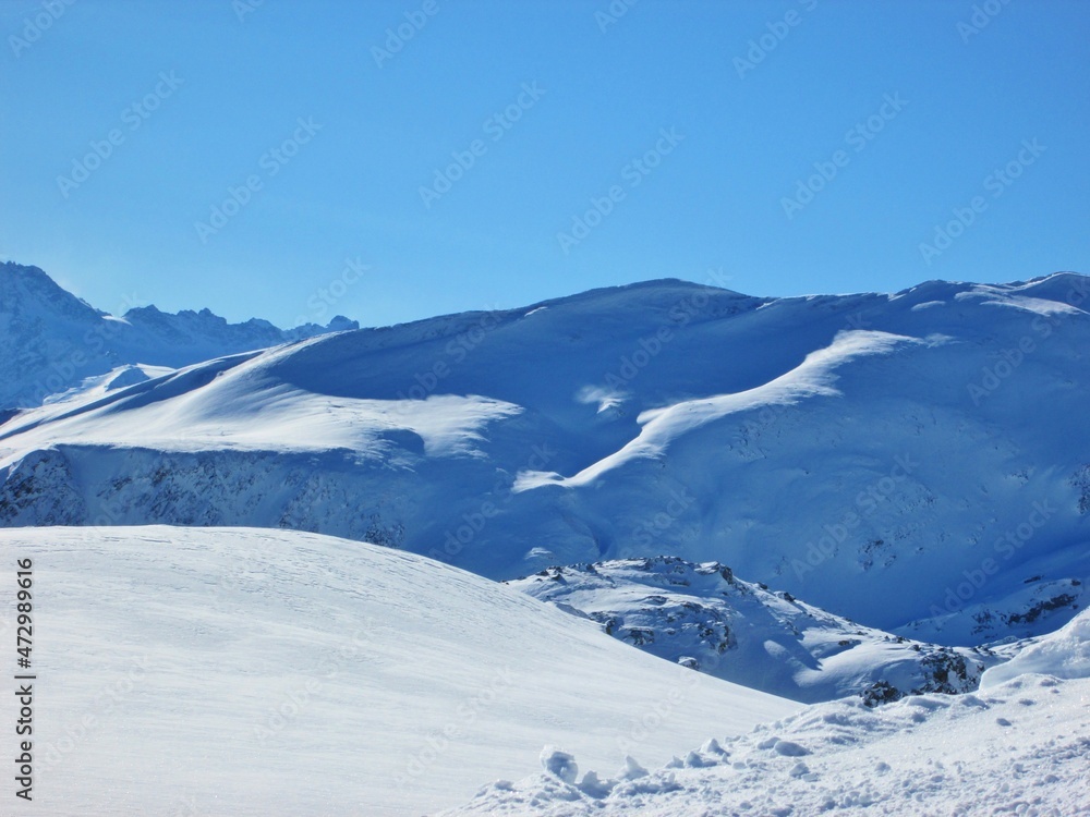 Winter landscape in Saint Sorlin d'Arves - Les Sybelles. Winter desert. Mountains against blue sky in French Alps. Sunny day in ski resort. Fun during holidays. Ski business. Alps and snow.
