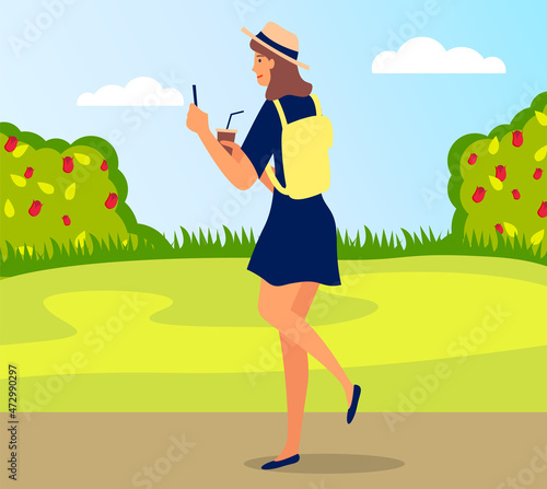 Young happy woman walking in park with mobile phone and coffee using smartphone to share posts and news in social networks, chatting with friends. Girl holds smart phone to make repost of video