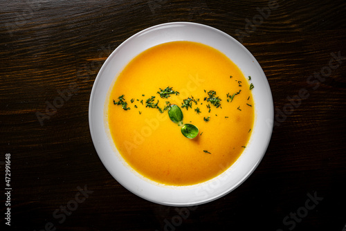 Pumpkin soup in white plate on black wooden table background